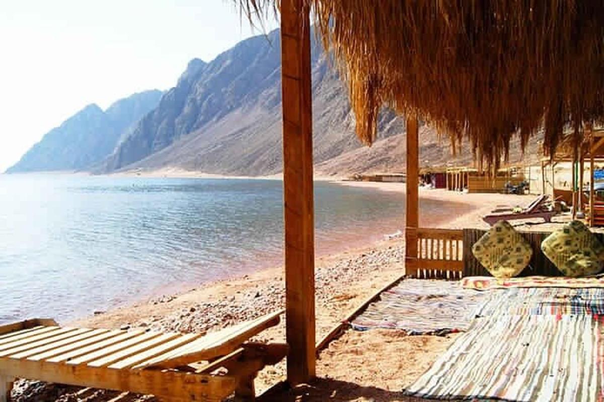 una spiaggia con sedie e un ombrellone e l'acqua