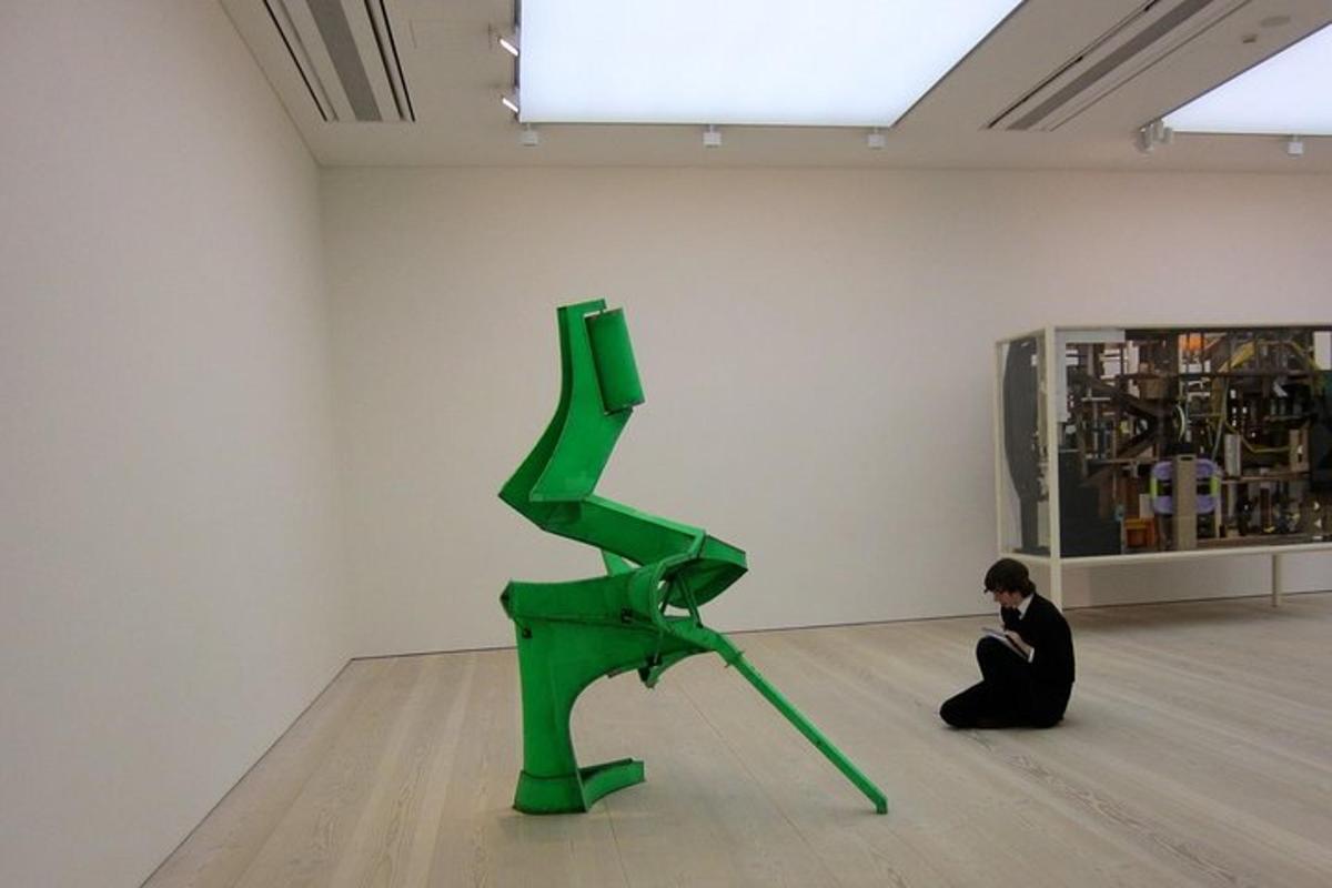 a man sitting on the floor next to a green sculpture