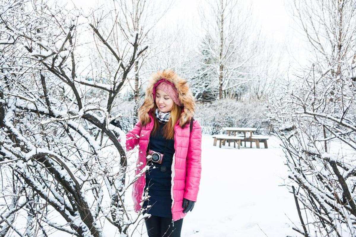 一位身穿粉色夹克的女子站在雪地里