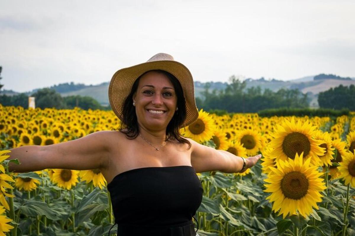 uma mulher de chapéu em pé em um campo de girassóis