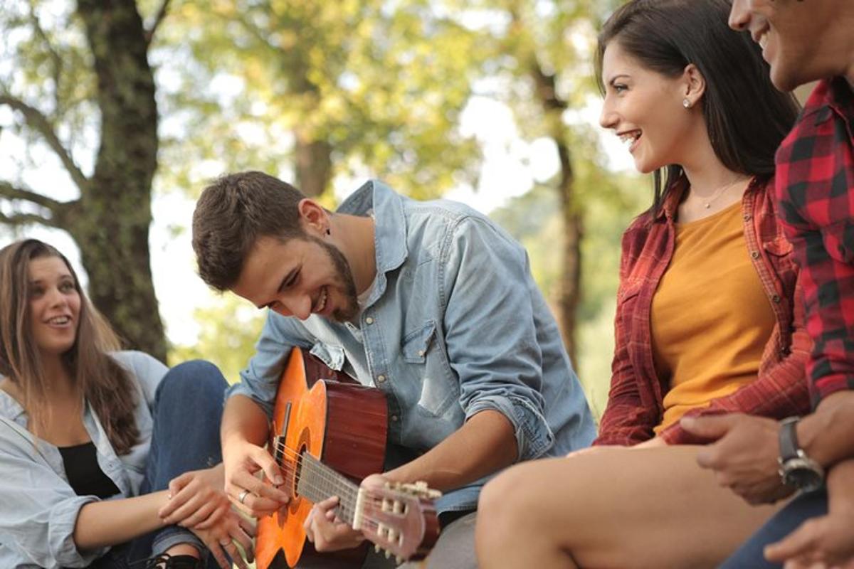 egy csoport ember ül egy gitározó férfi körül