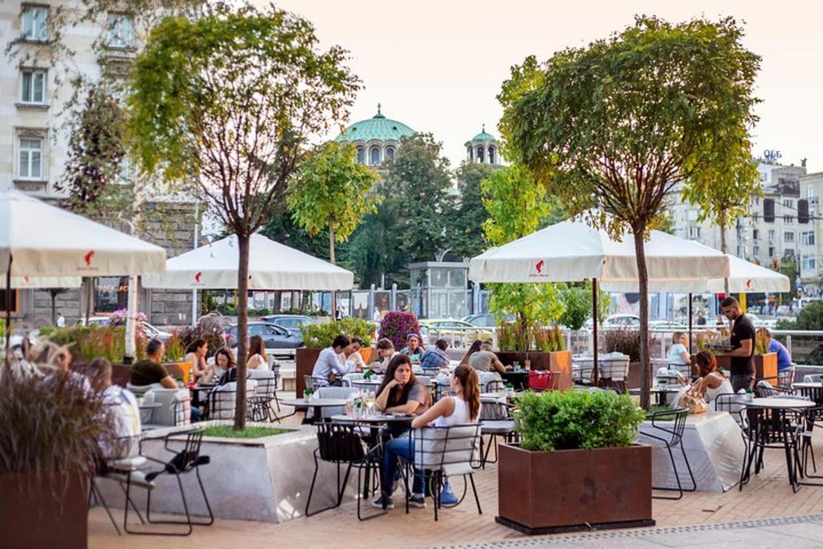 Un grupo de personas sentadas en mesas en un restaurante al aire libre.