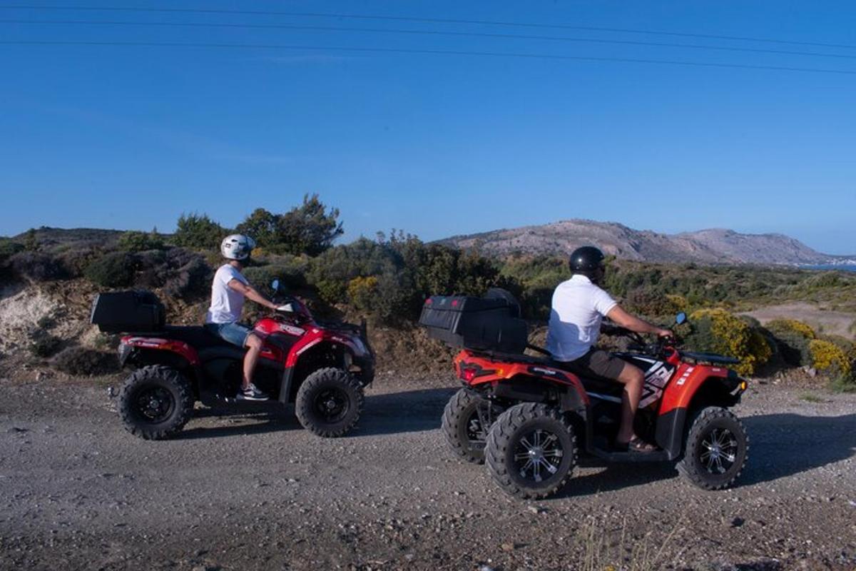 due persone che guidano un quad su una strada sterrata