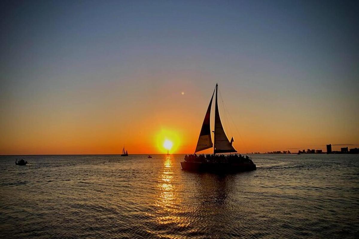 a sail boat in the water at sunset
