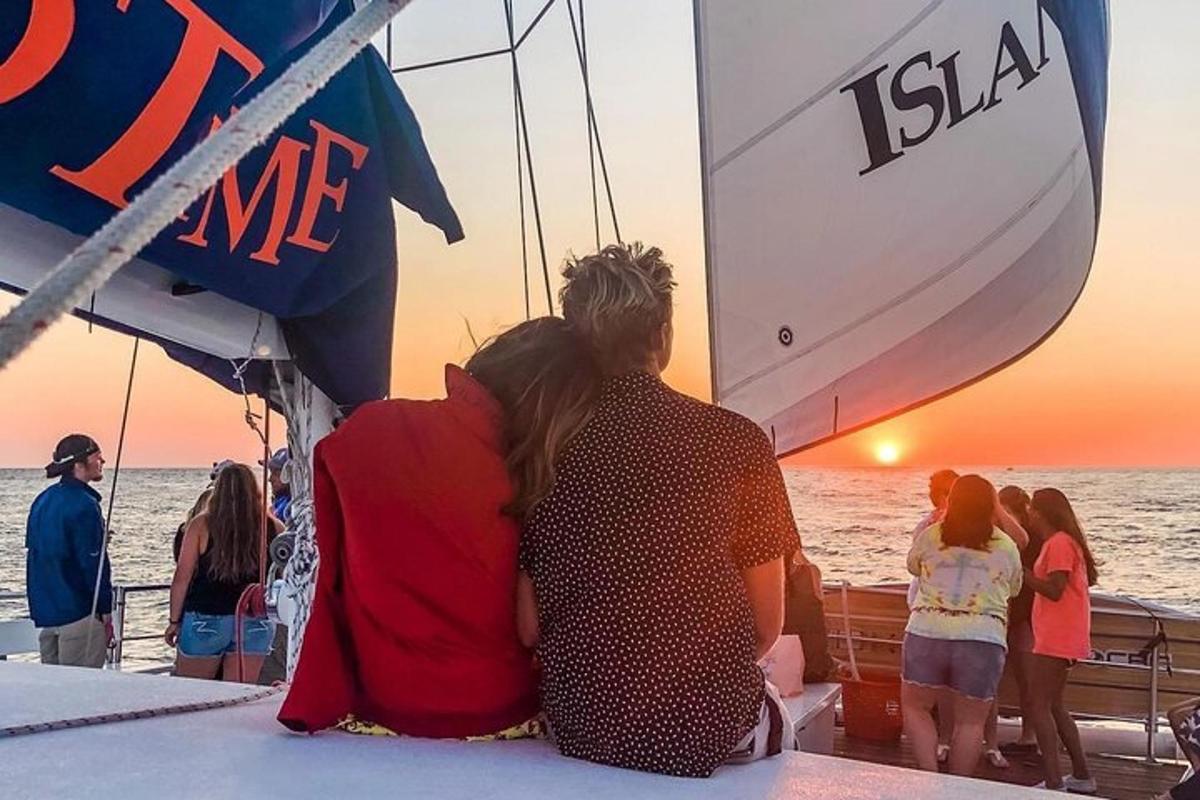 due persone sedute su una barca che guardano il tramonto