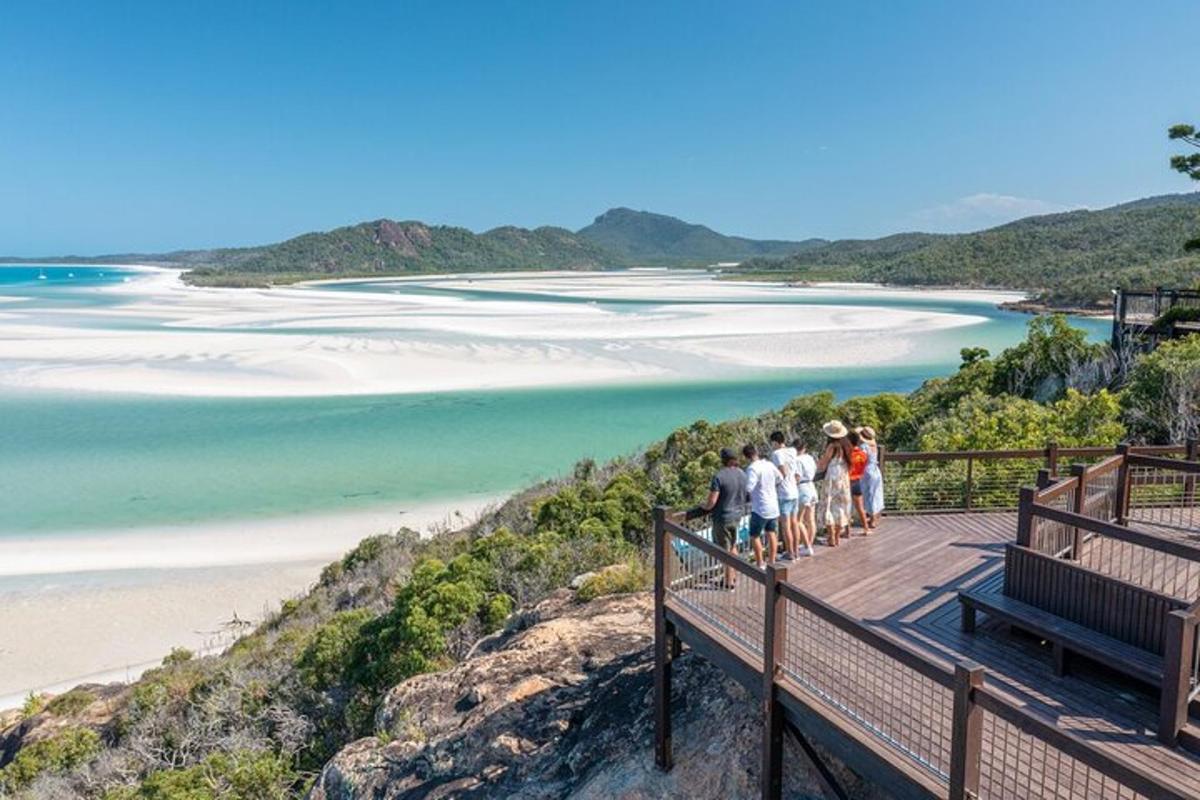 a group of people standing on a boardwalk overlooking a beach