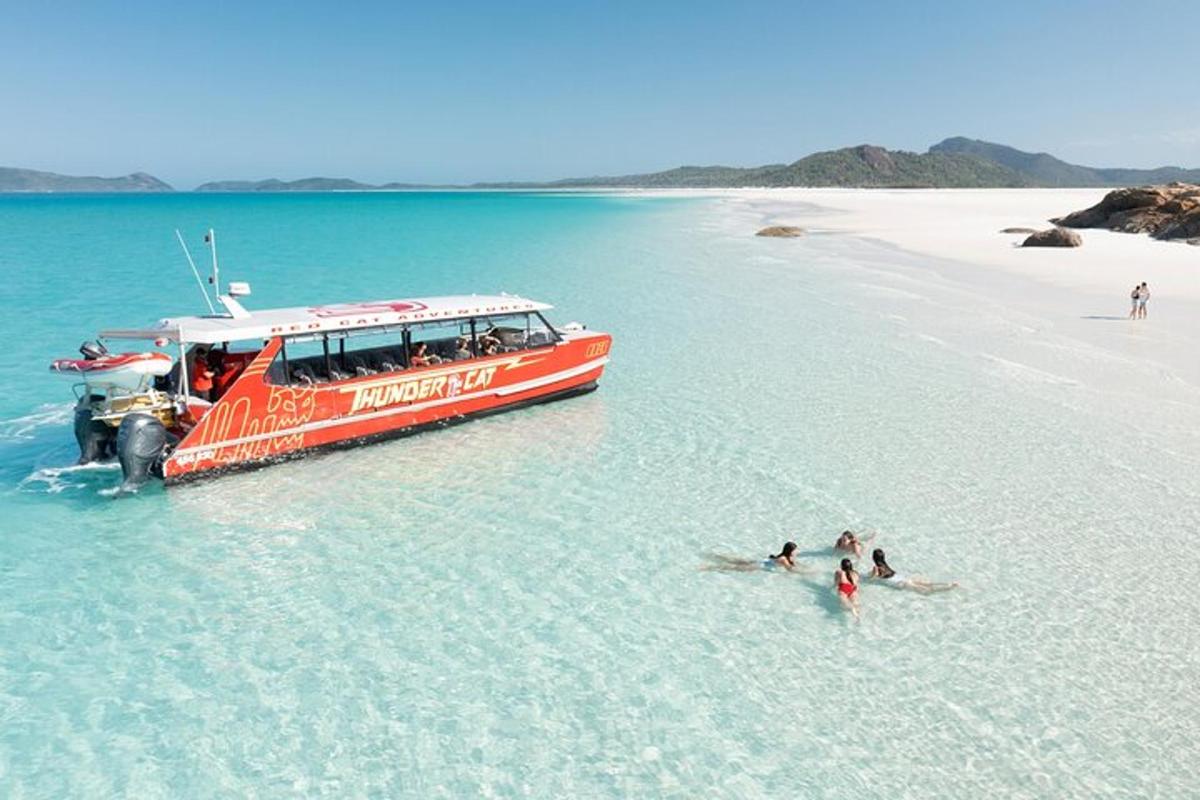 a red boat in the water next to a beach