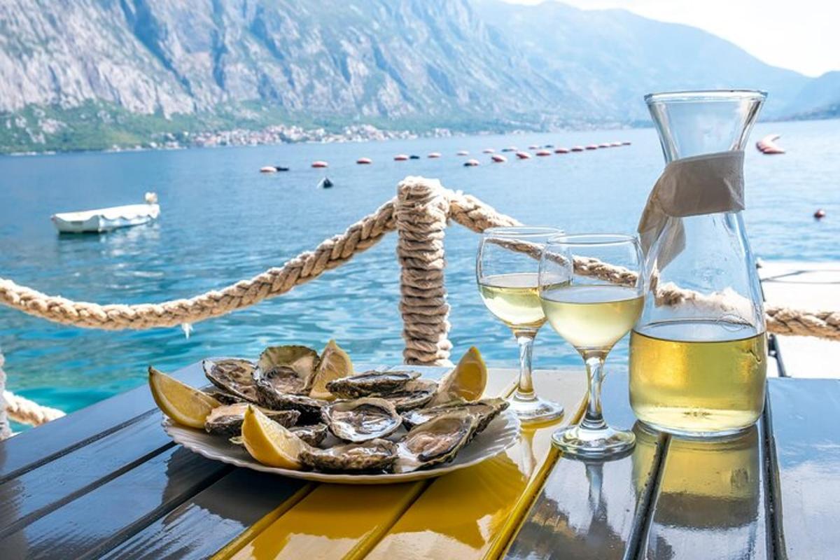 uma mesa com um prato de ostras e taças de vinho