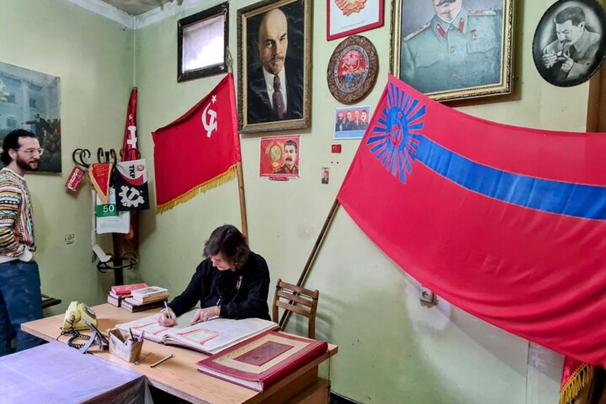 egy nő ül egy asztalnál egy szobában, egy zászlóval a kezében