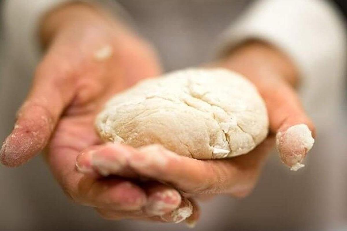 một người đang cầm một miếng bánh mì trên tay