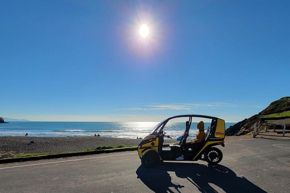 uma pessoa dirigindo um carrinho de golfe em uma estrada perto da praia