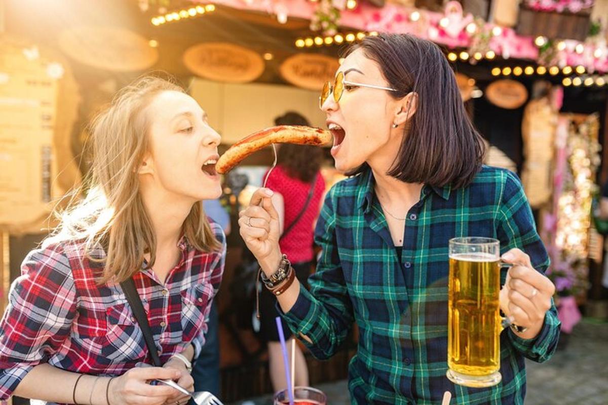 two women eating a piece of pizza and drinking beer