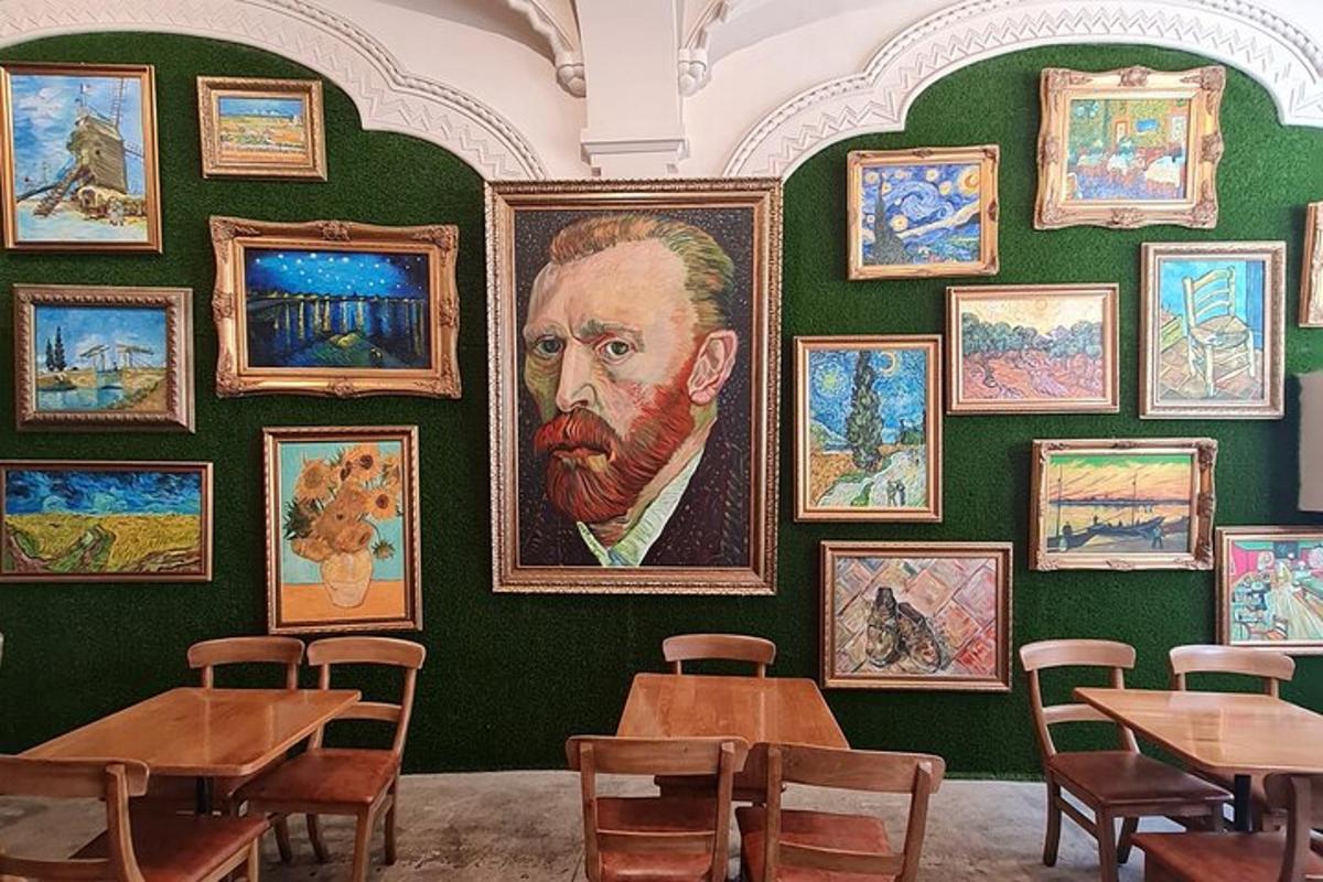 a room with tables and paintings on a green wall