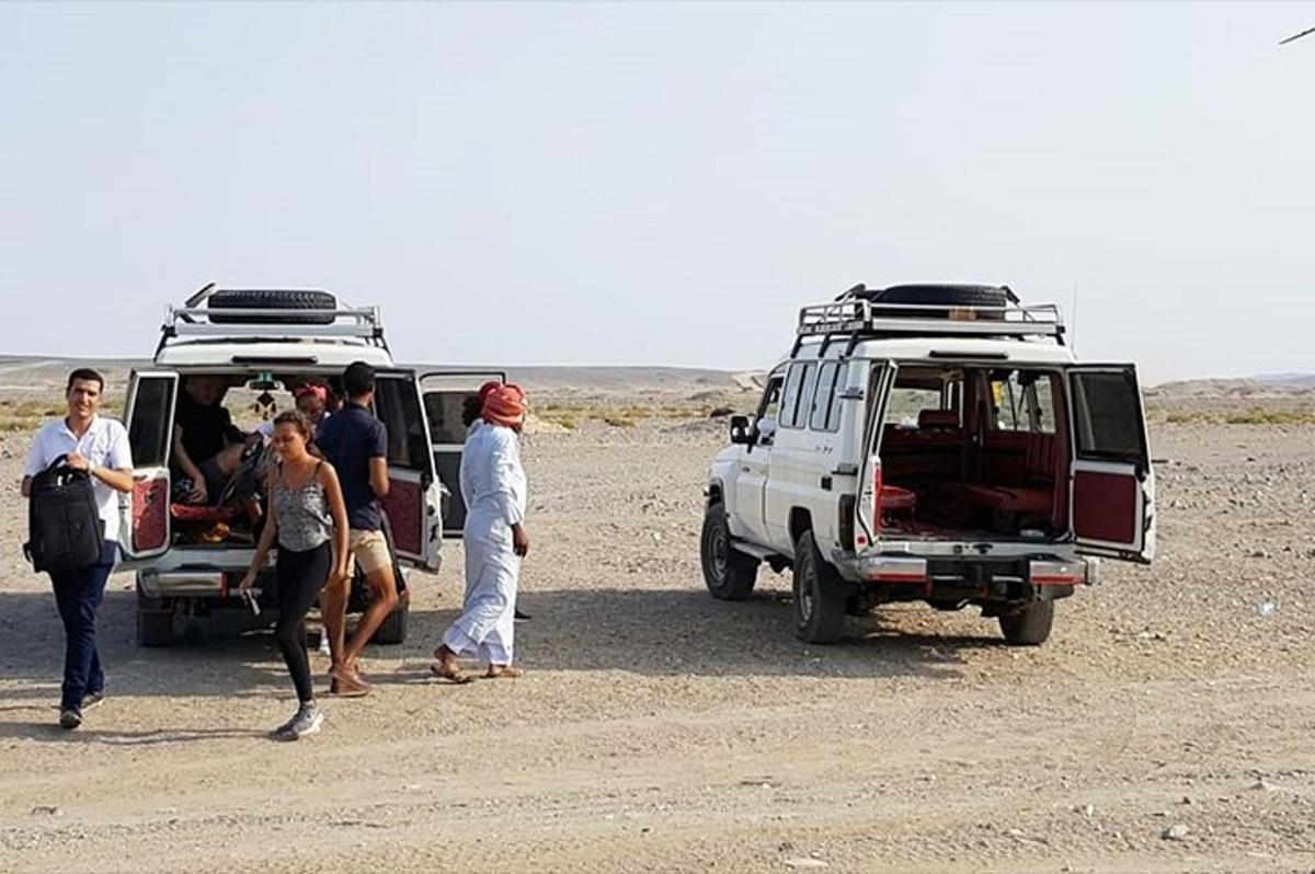 un gruppo di persone in piedi accanto alle loro auto nel deserto