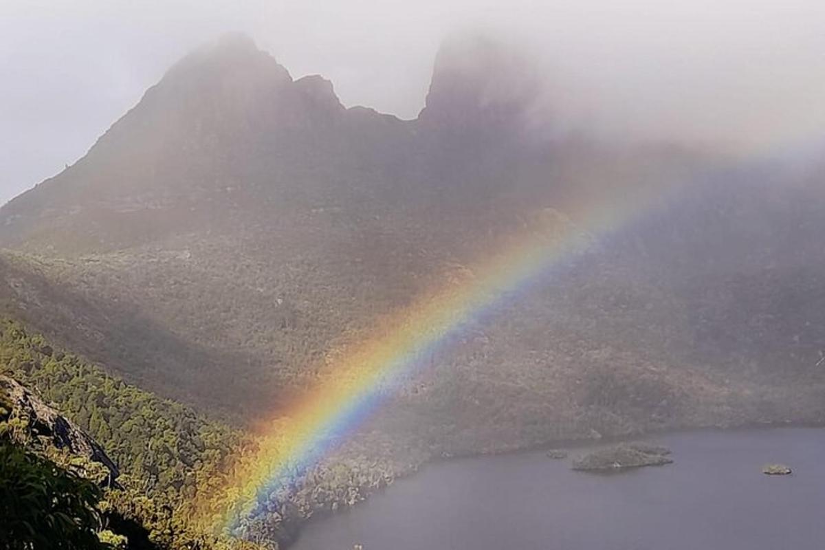 a rainbow over a lake with a mountain