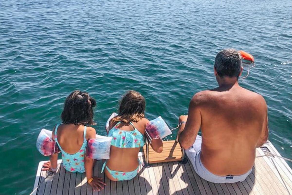 um homem e duas meninas sentados em um barco na água