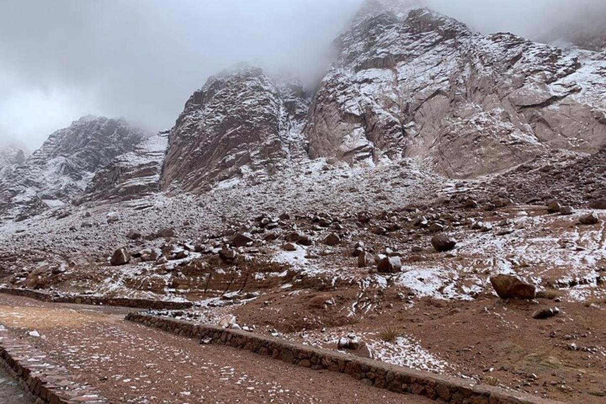 et fjell med snø på og en grusvei