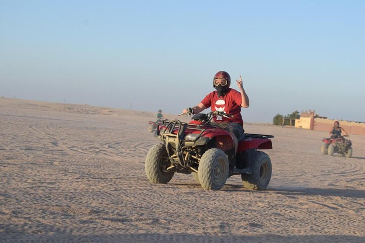 seorang lelaki menunggang basikal quad di padang pasir