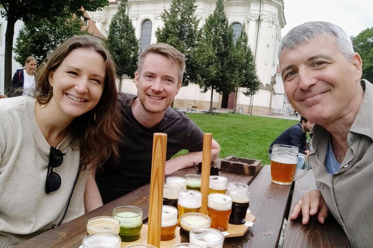 um grupo de três pessoas sentadas à mesa com cervejas