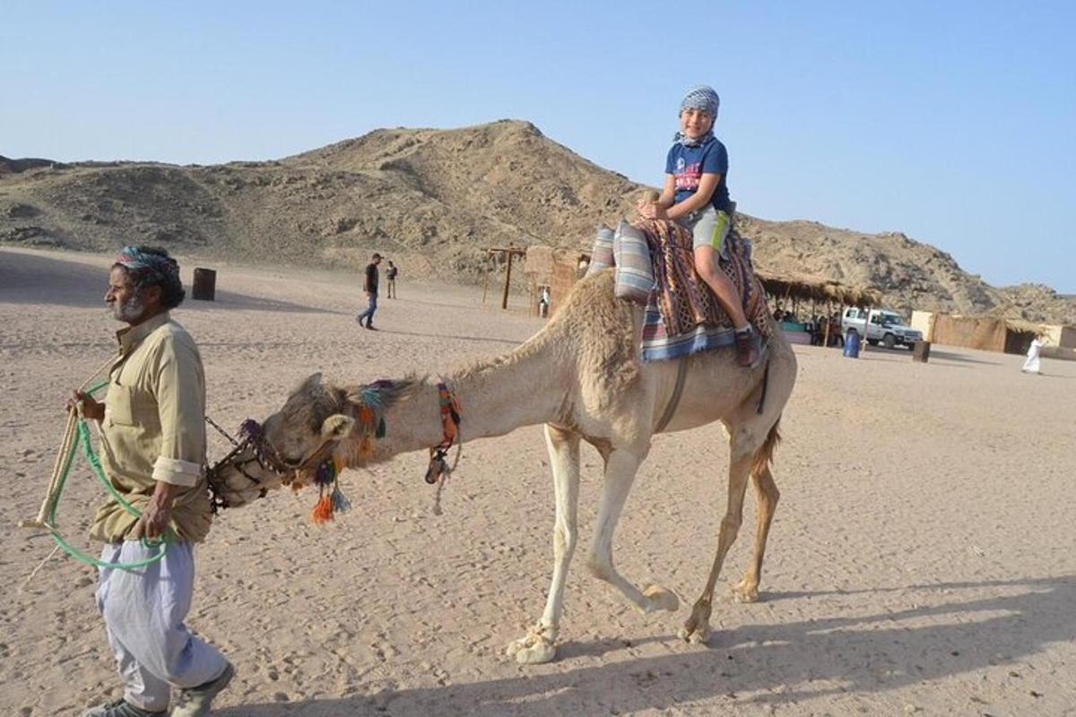 un uomo e un ragazzo su un cammello nel deserto