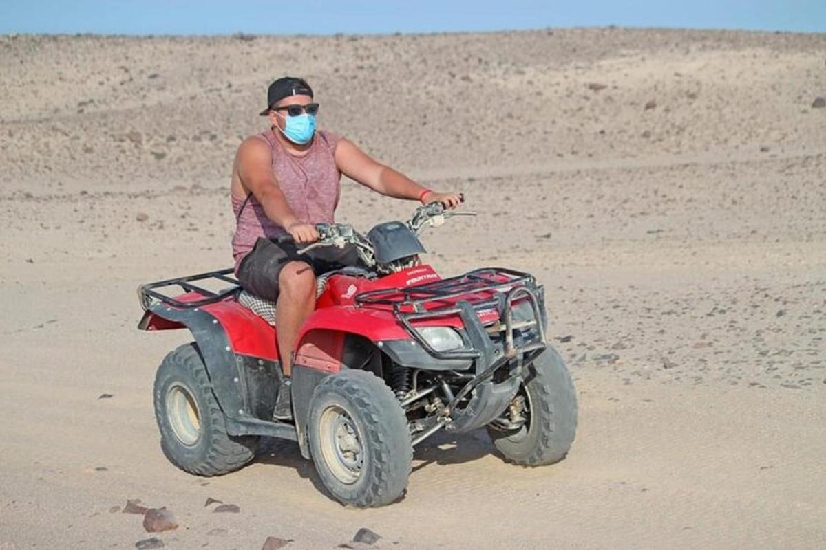 un uomo in sella a un quad nel deserto