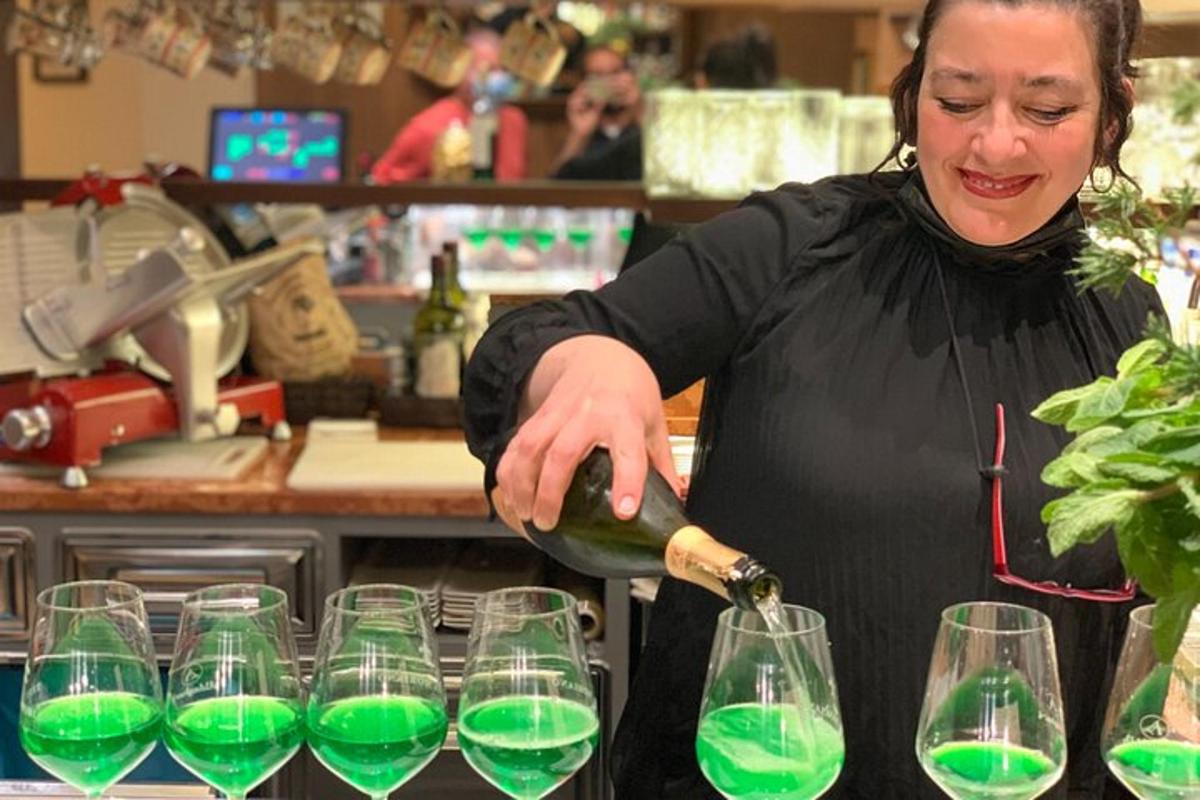 uma mulher servindo vinho em copos em uma cozinha