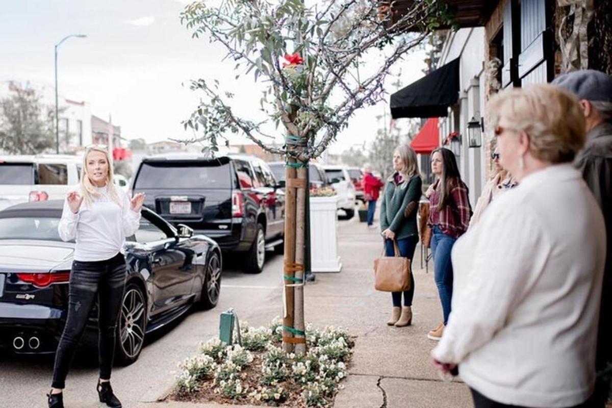 a woman standing on a sidewalk next to a tree