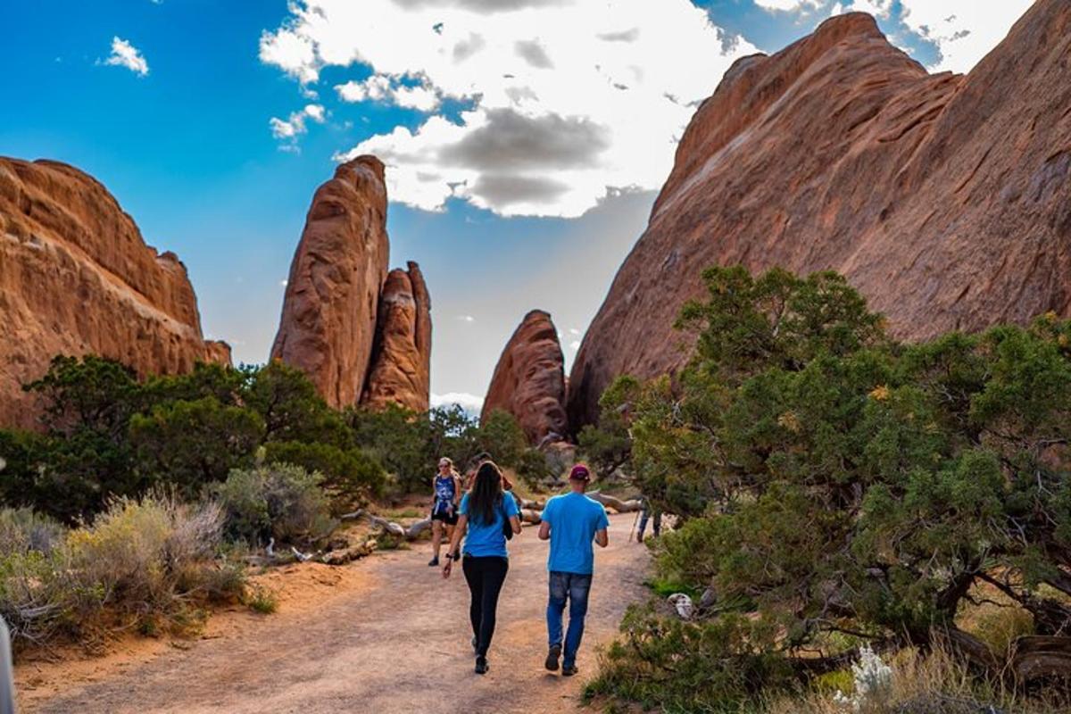 a group of people walking down a dirt road through a canyon