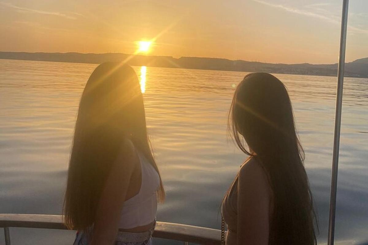two women standing on a boat watching the sunset
