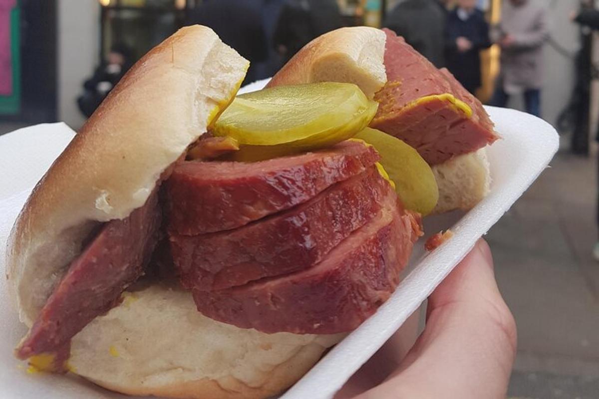 osoba držící hot dog s okurkami