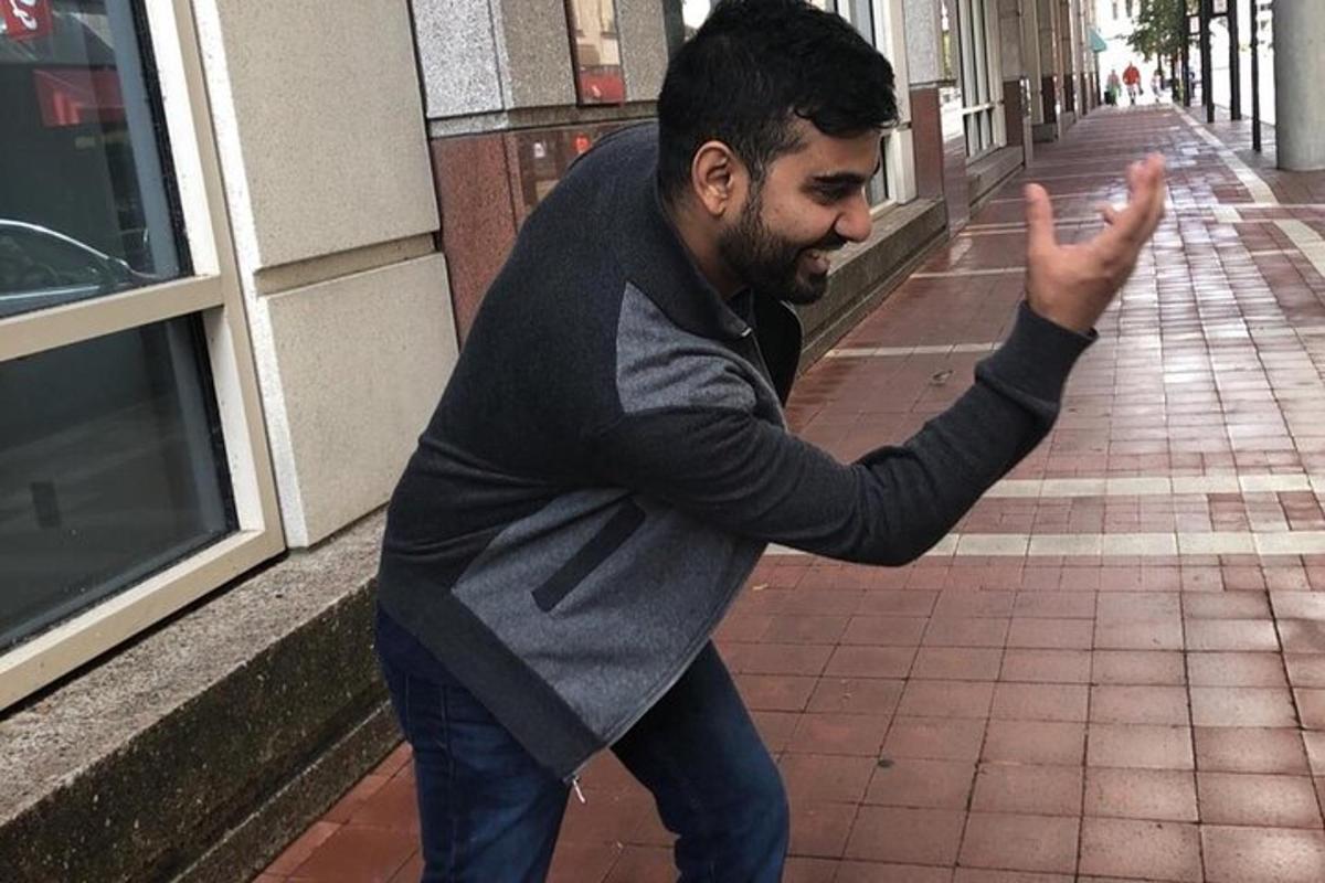 vīrietis stāv uz ietves ar paceltu roku