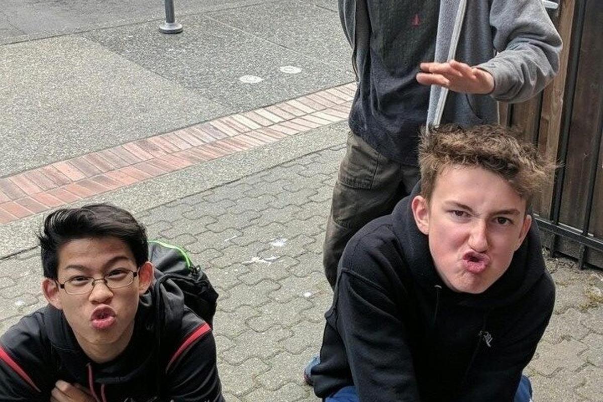 two young men sitting on the ground with their mouths