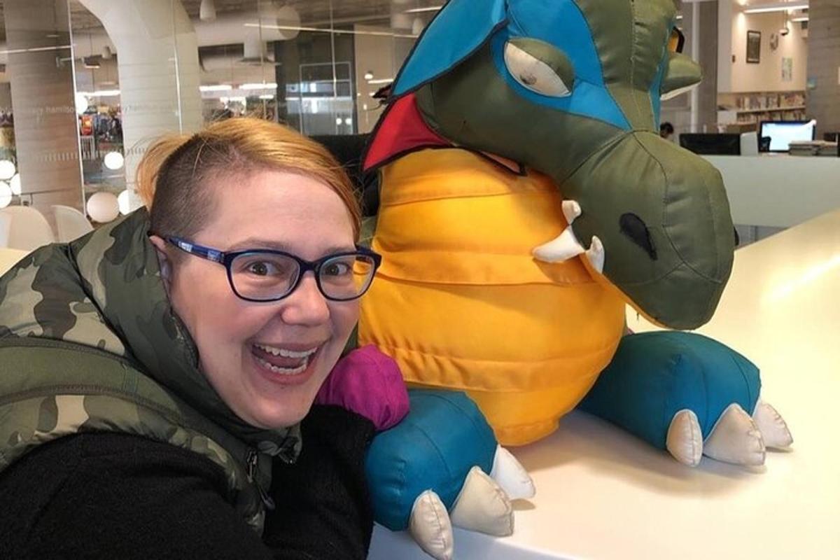 a woman is smiling next to a stuffed animal