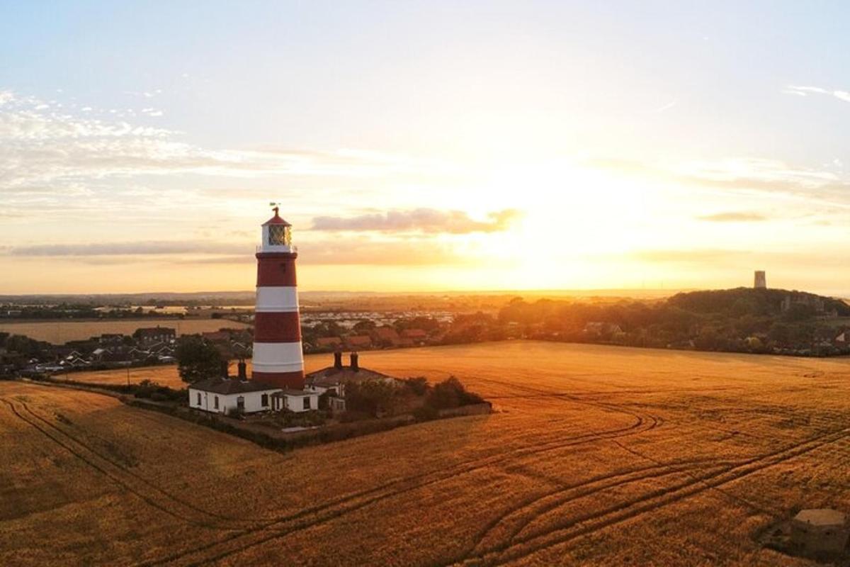 a lighthouse on a field with the sunset in the background