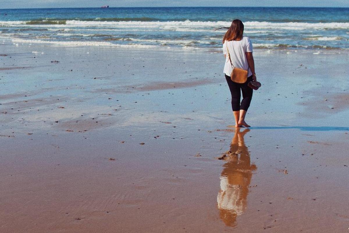 a woman standing on the beach looking at the ocean