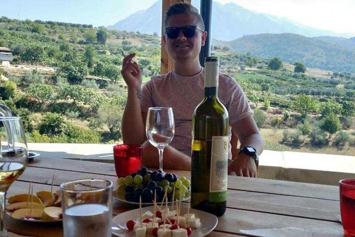 a man sitting at a table with a bottle of wine