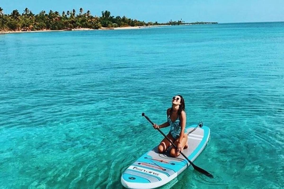 a woman sitting on a paddle board in the water