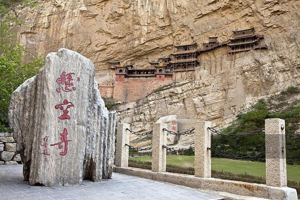 a stone fence with chinese writing on it in front of a mountain