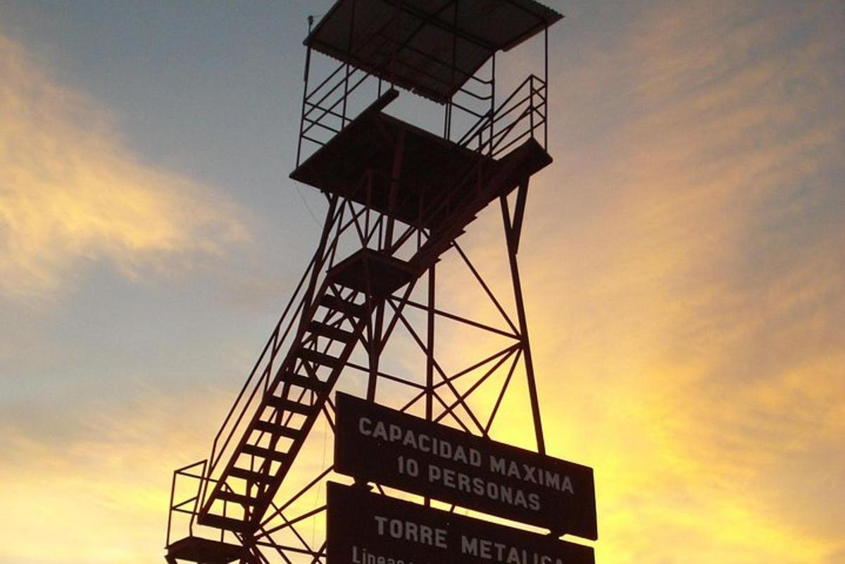 a sign in front of a water tower with the sunset