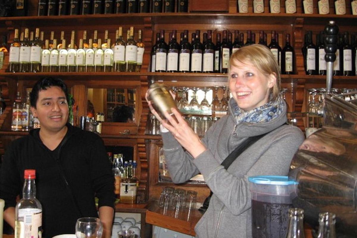 o femeie care stă la un bar și ține în mână o sticlă de vin
