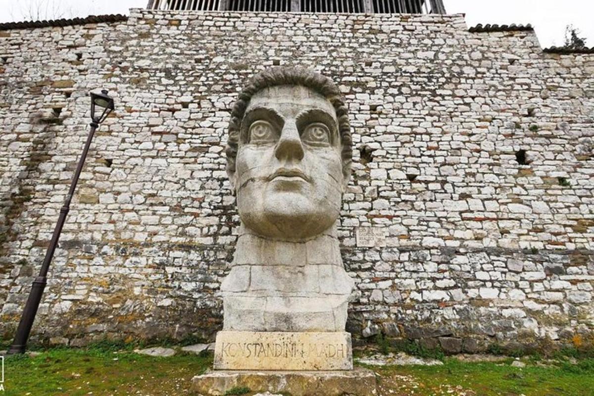 una estatua de una cabeza frente a una pared de ladrillos