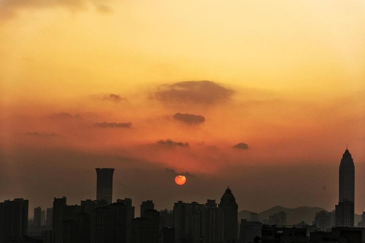 a city skyline with the sun setting in the sky