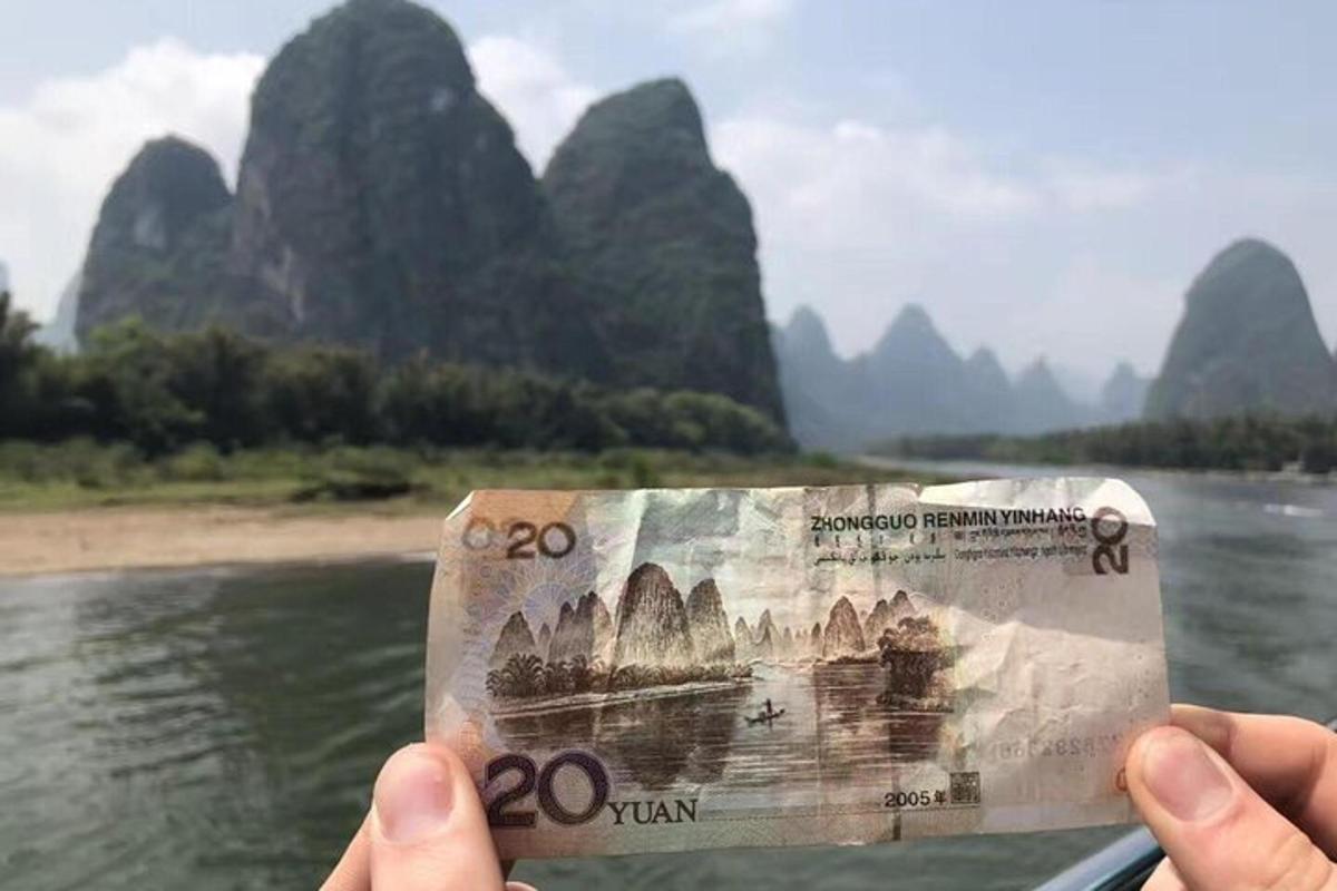 a person holding a yuan banknote in front of a river