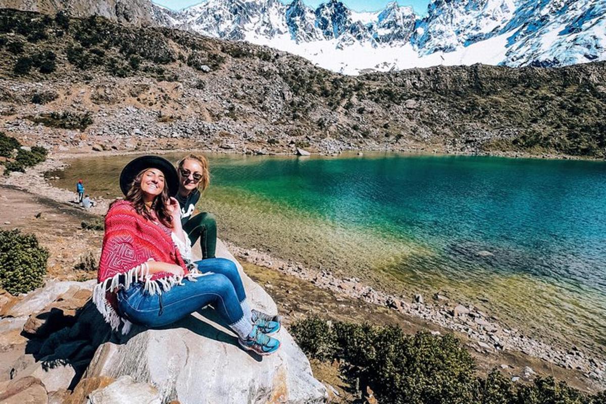 a man and a woman sitting on a rock near a lake