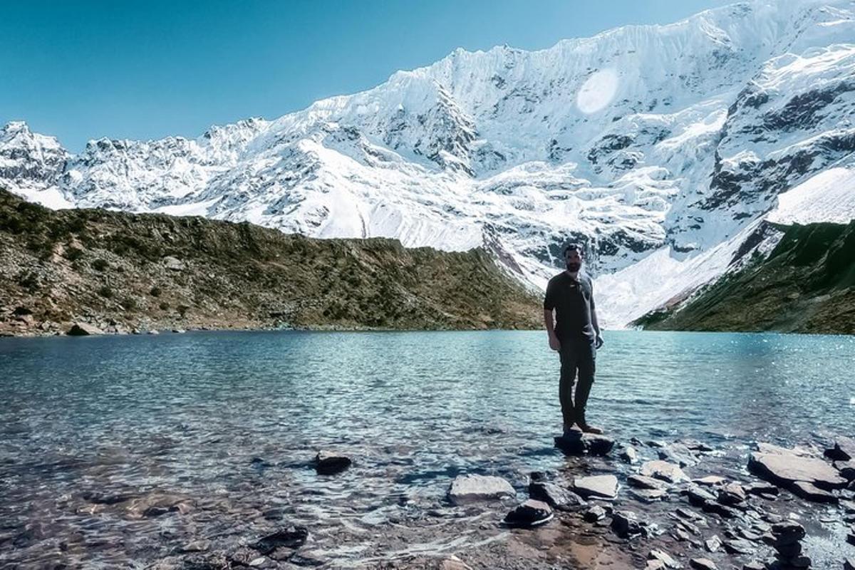a man standing on a rock near a mountain lake