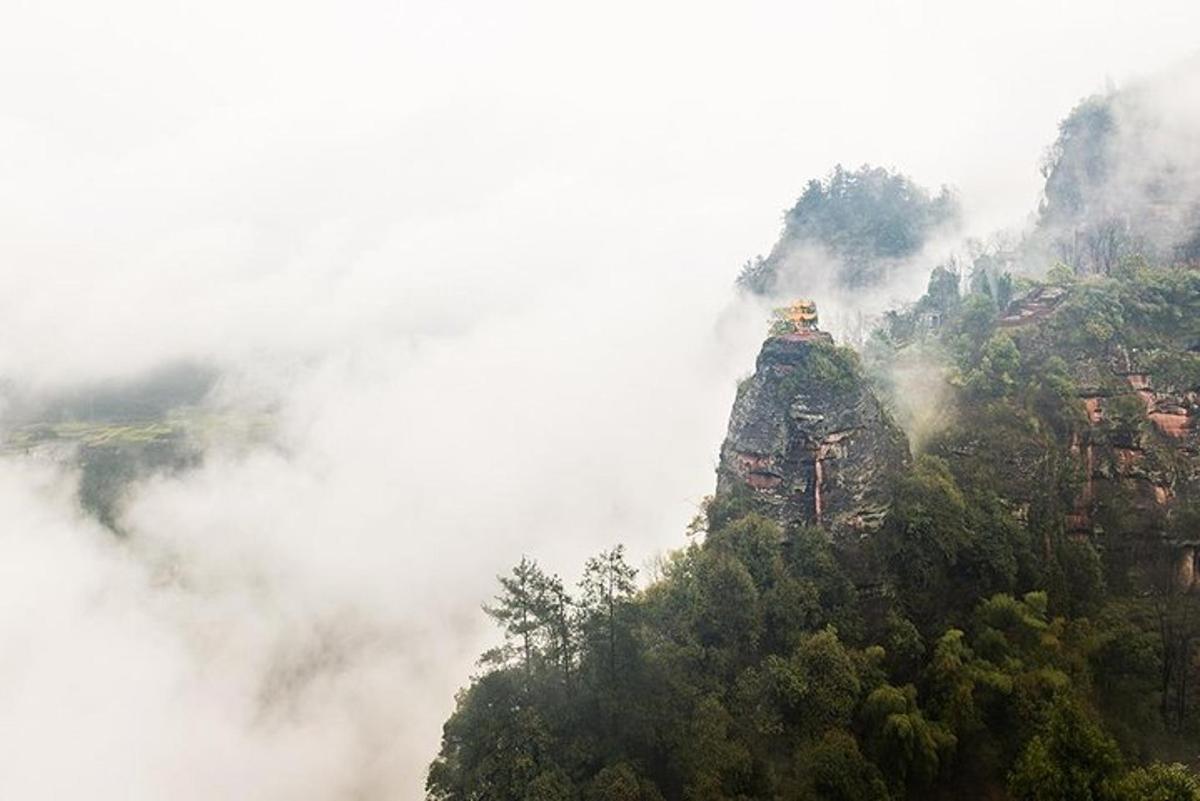 una montaña en las nubes con un edificio en la cima