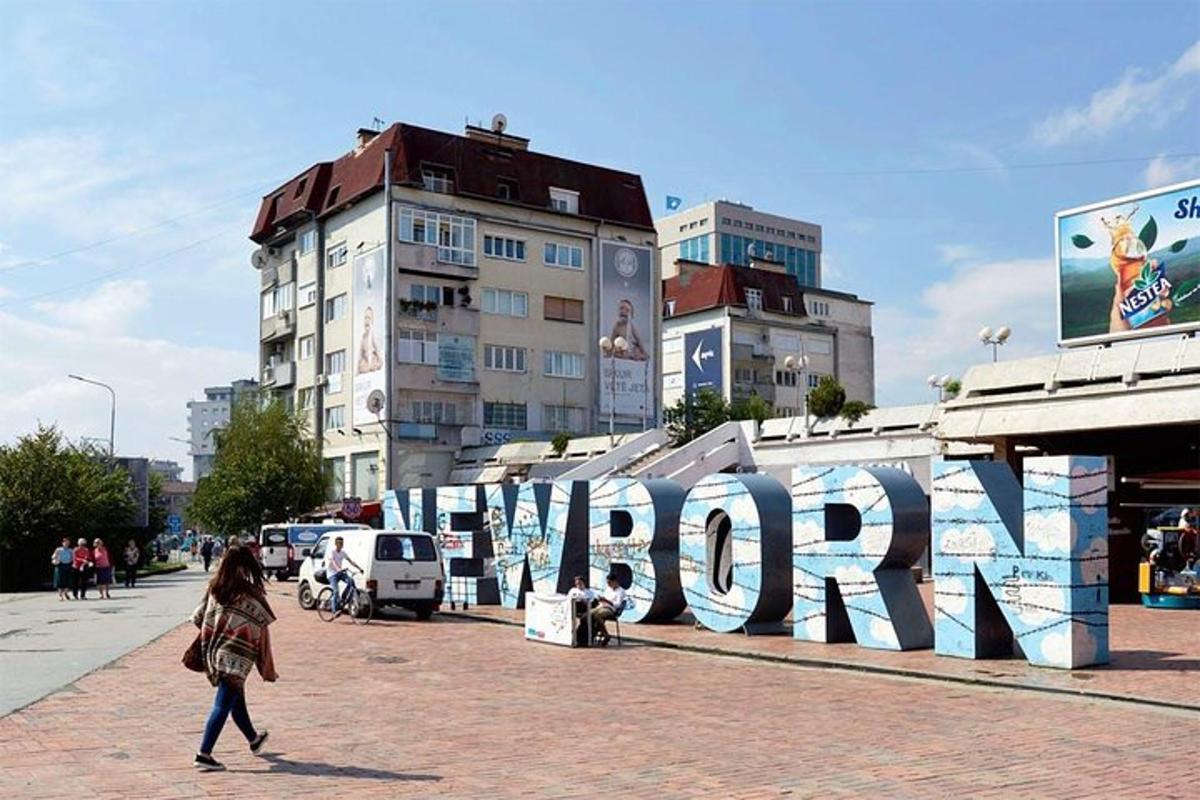 žena kráčející po ulici před nástěnnou malbou