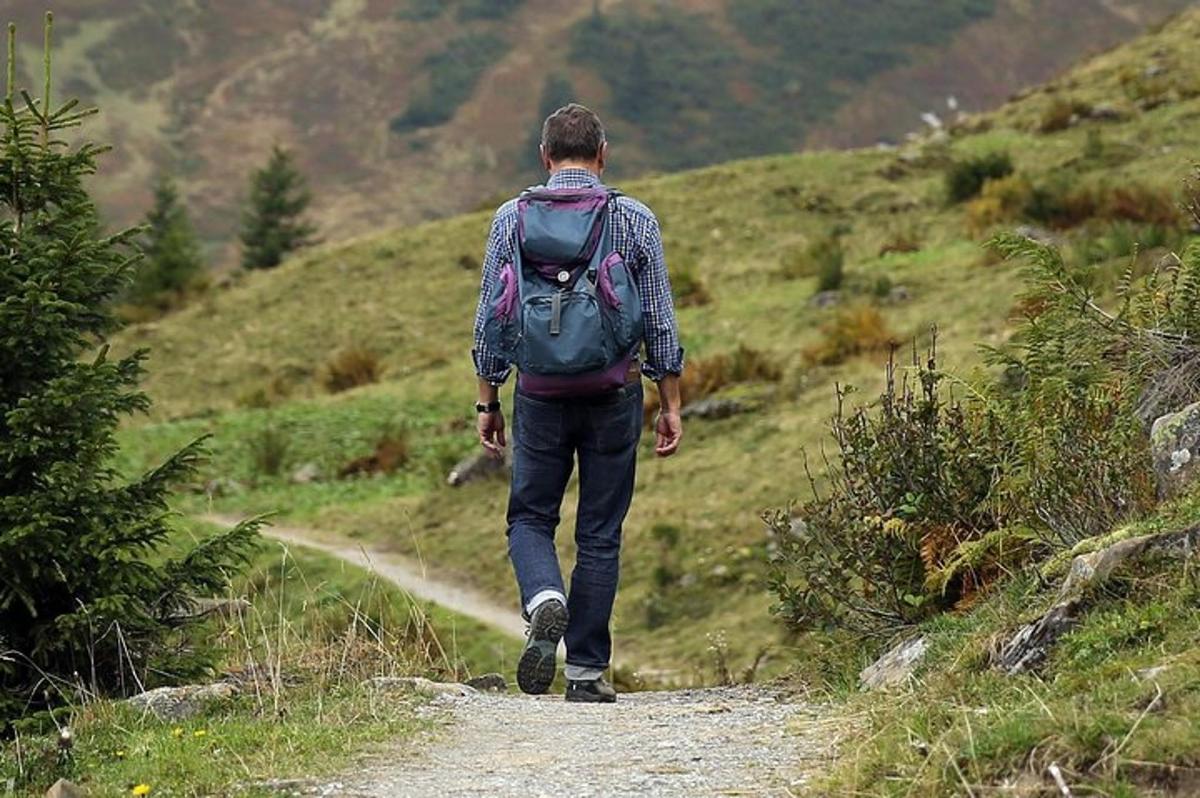 a man with a backpack walking down a trail