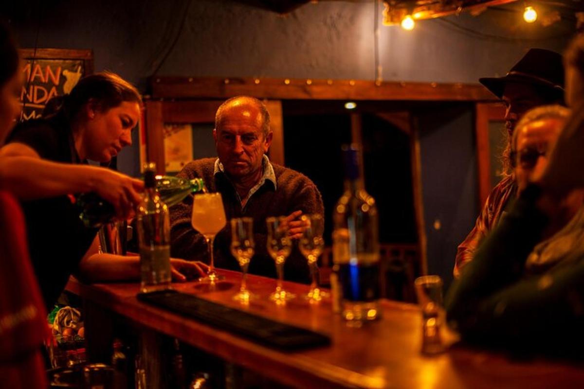 um grupo de pessoas em pé ao redor de um bar com taças de vinho