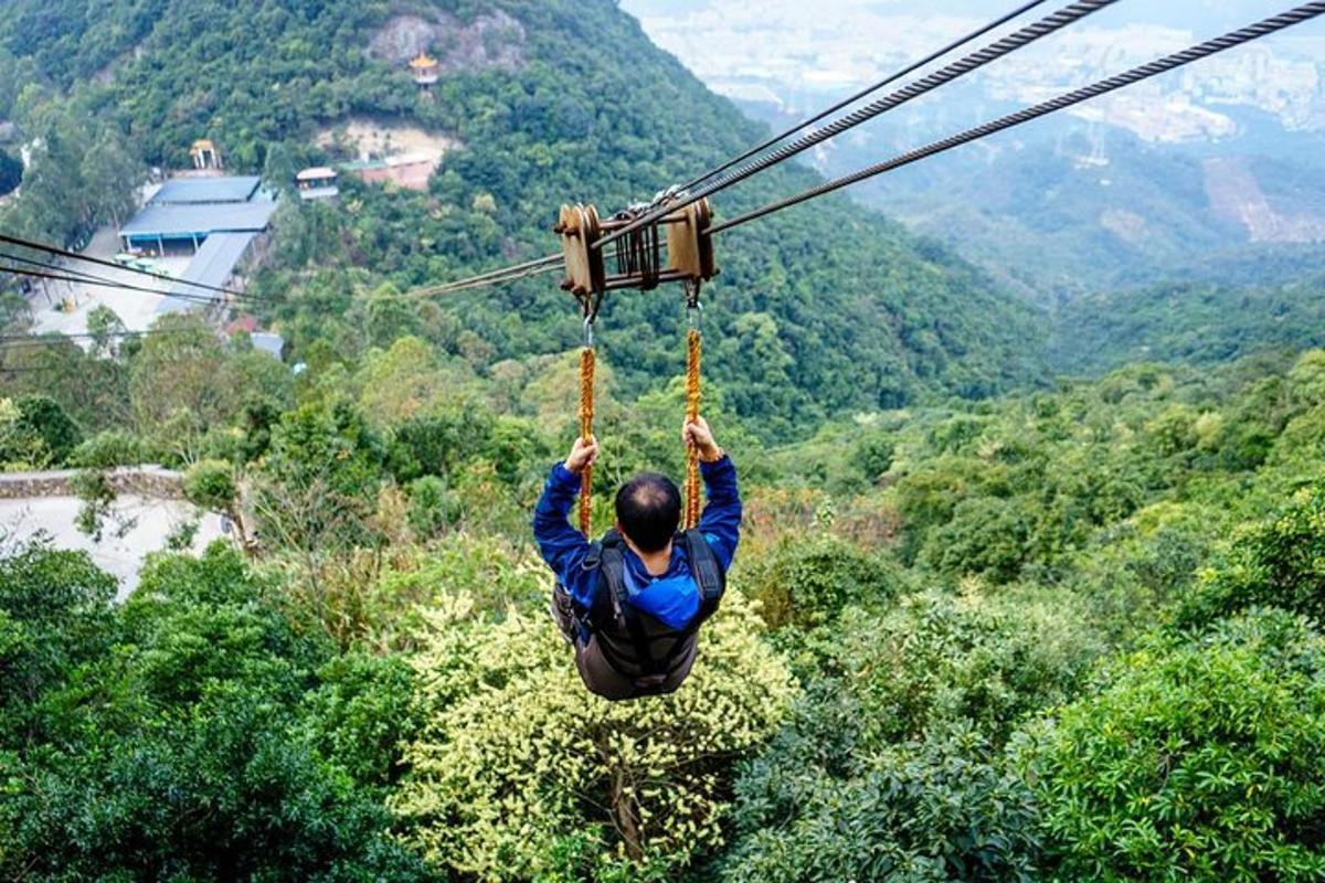 a man hanging from a zip line in the mountains